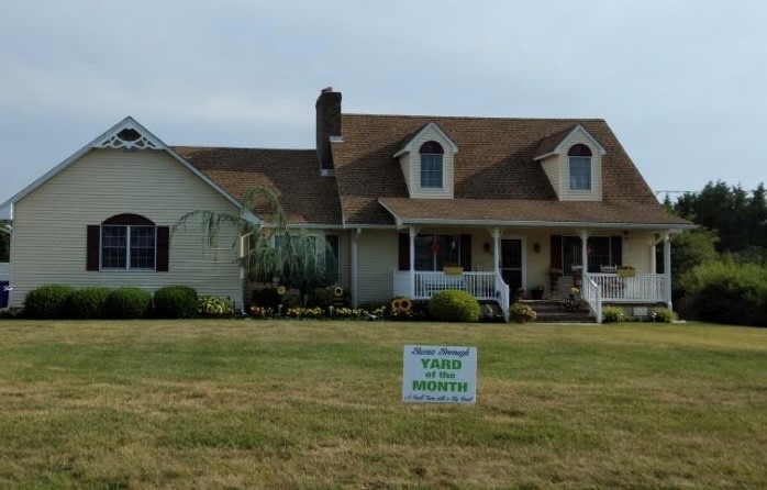 House that has a flowers and landscaping with the "Yard of the Month" lawn sign in front.
